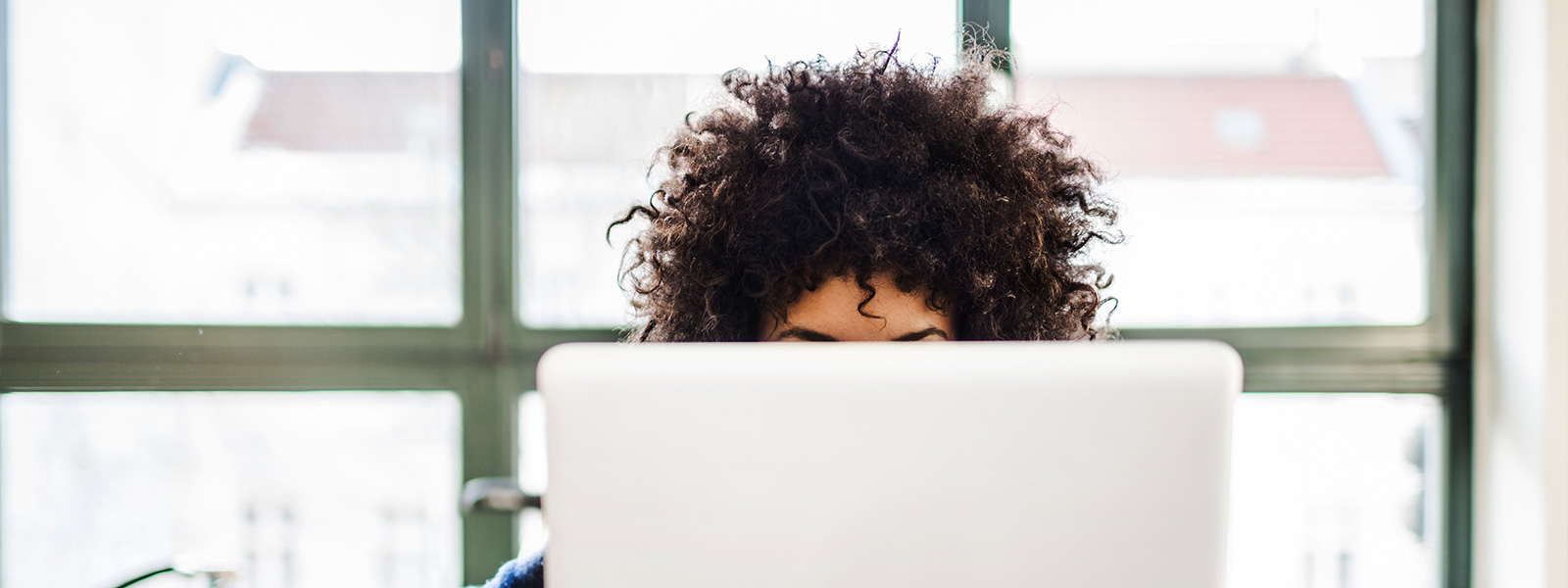 Woman with afro working on a laptop