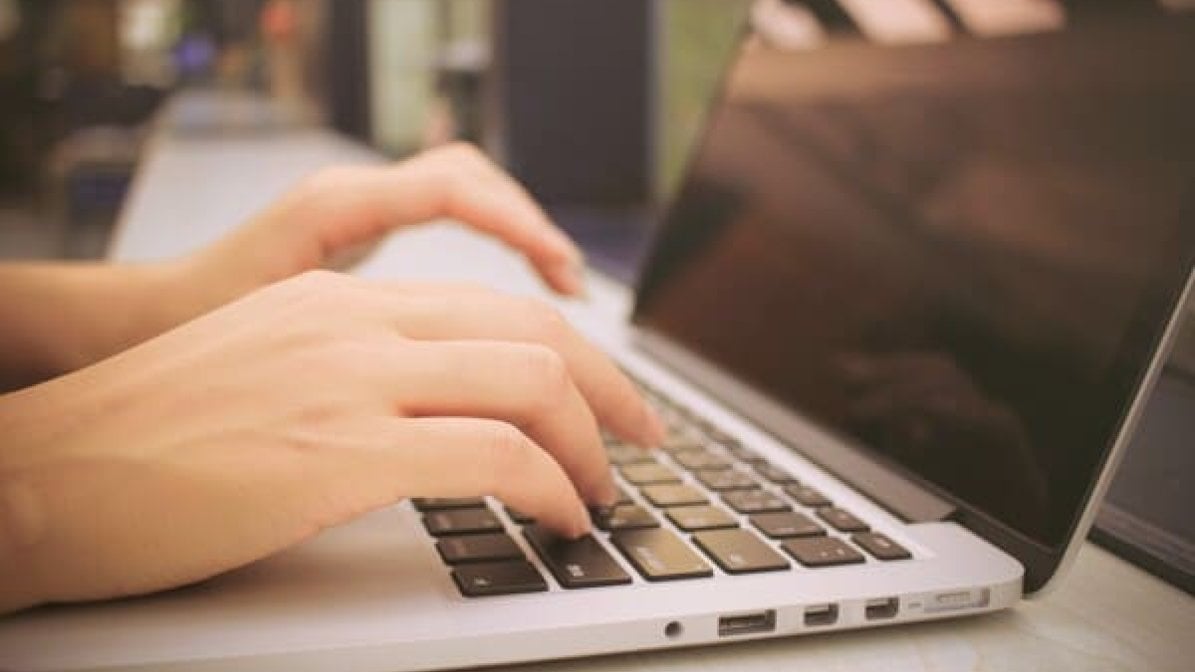 Person's hand typing on laptop 