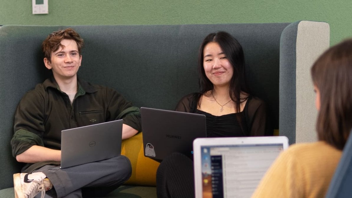 Group of students in uni communal area working on laptops
