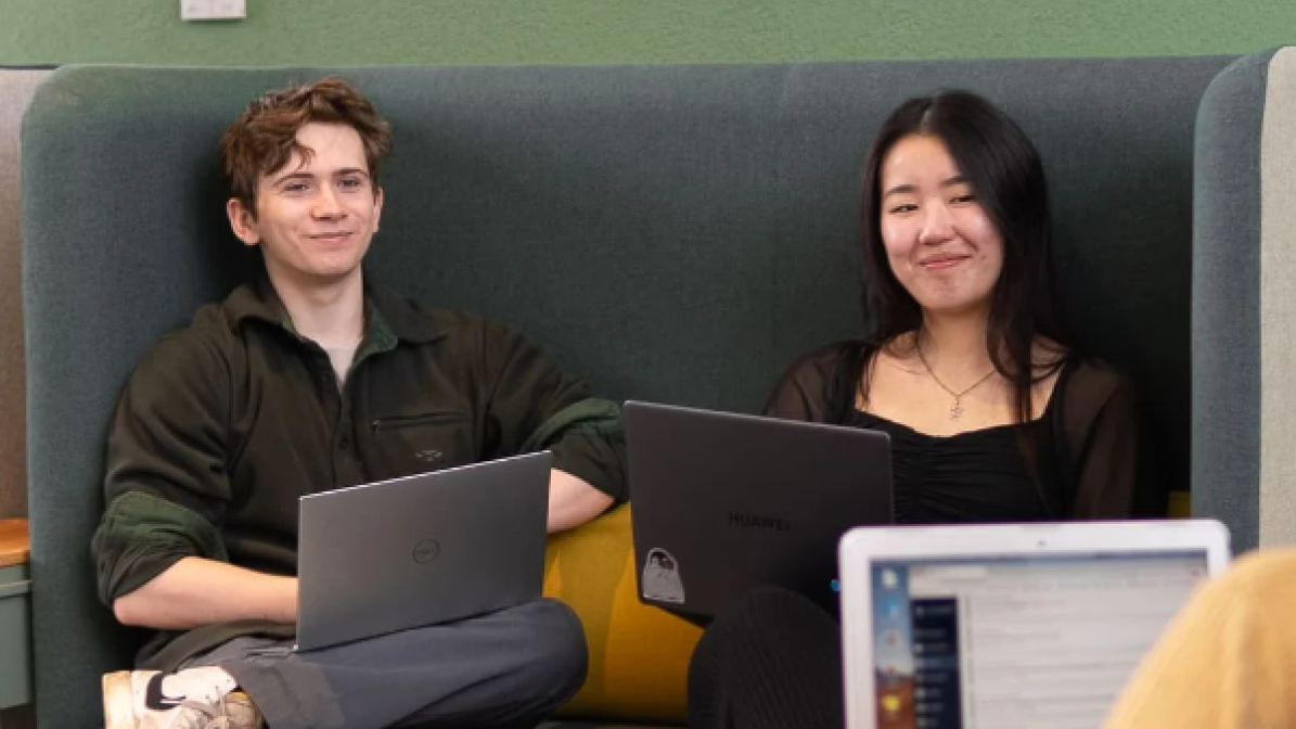 Students using laptops in communal area at university