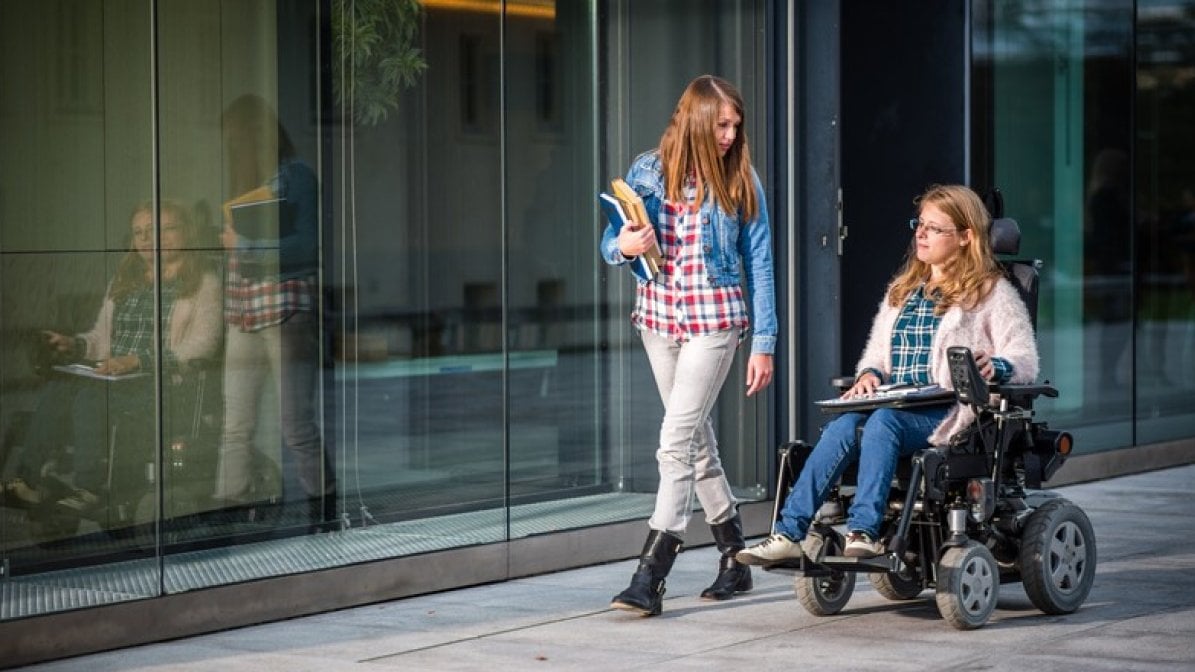 Two students - one in wheelchair- in university grounds