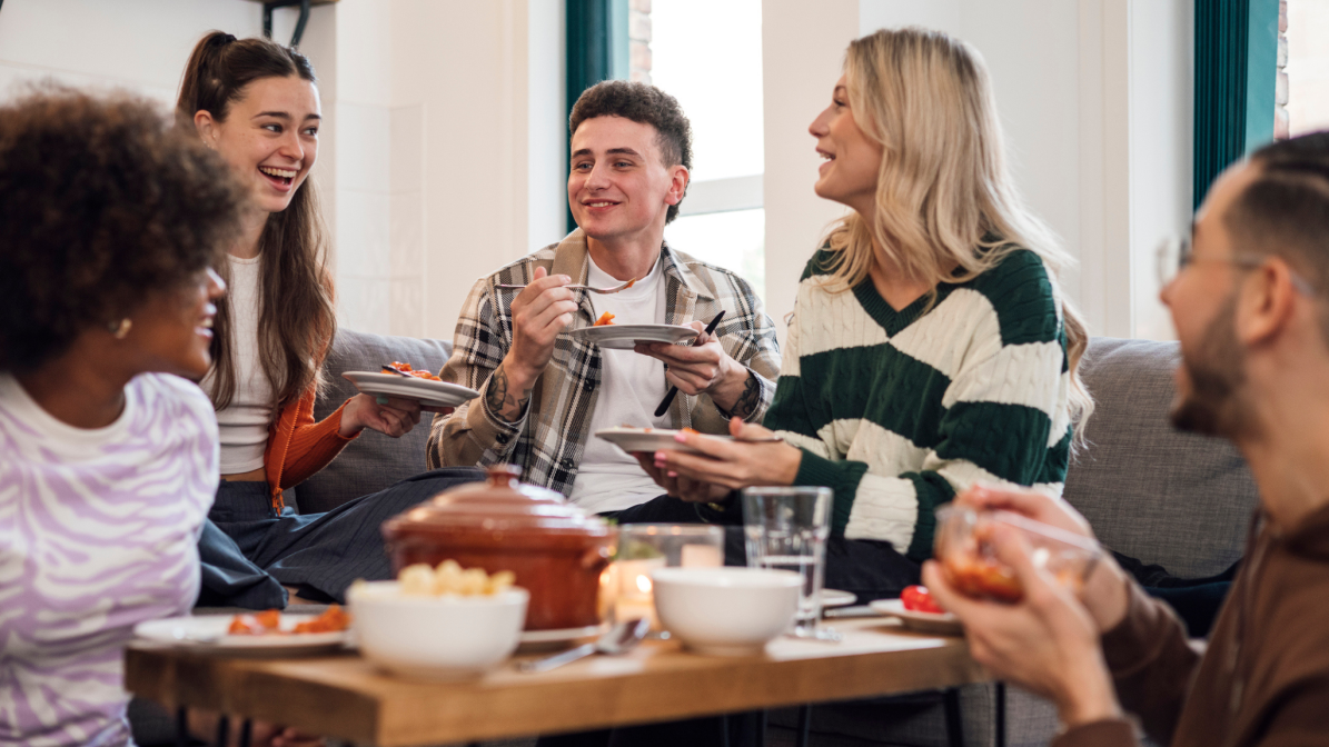 UCAS_Media_ArticleAccom001_Image_Box_1 A cheerful group of students enjoying a meal together, sharing laughter and food around a table.