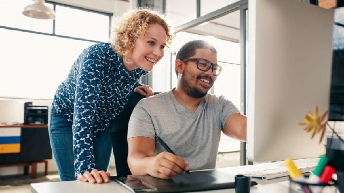 Disabled student using computer with assistant