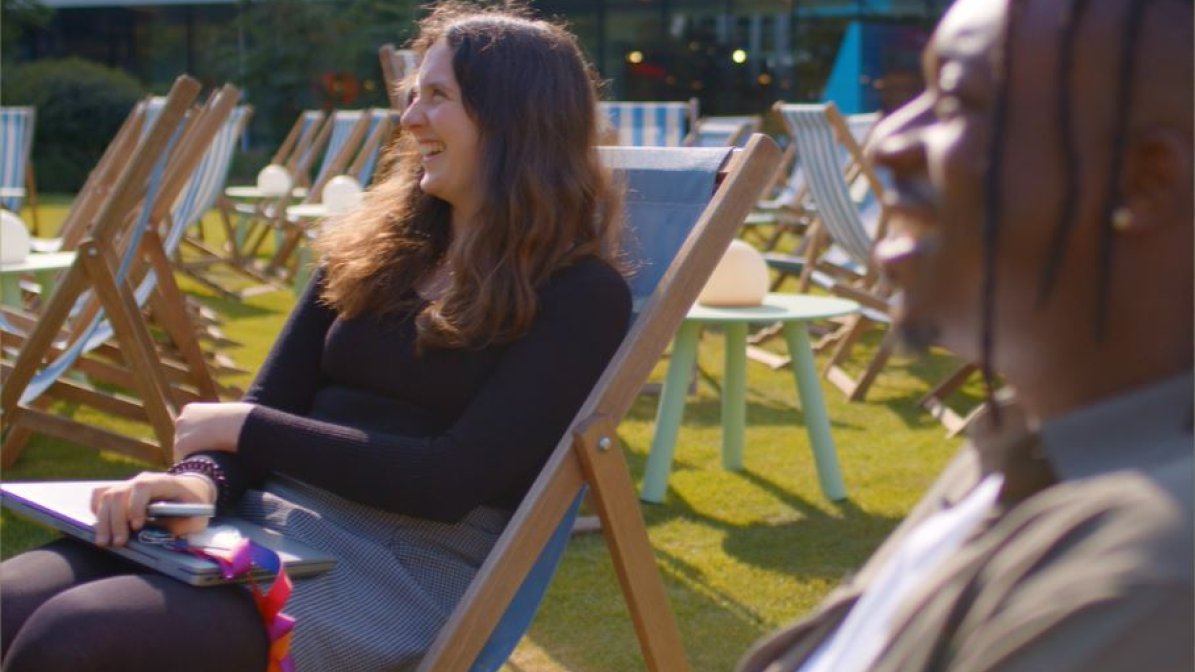 An image of two smiling Sky employees, sat outside on deckchairs