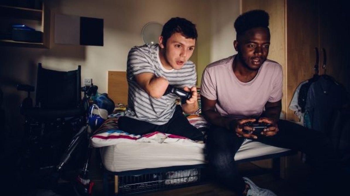 Two students playing computer games in a bedroom