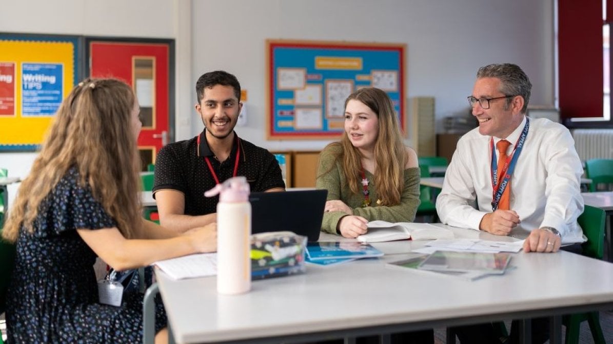 Adviser with students chatting in classroom