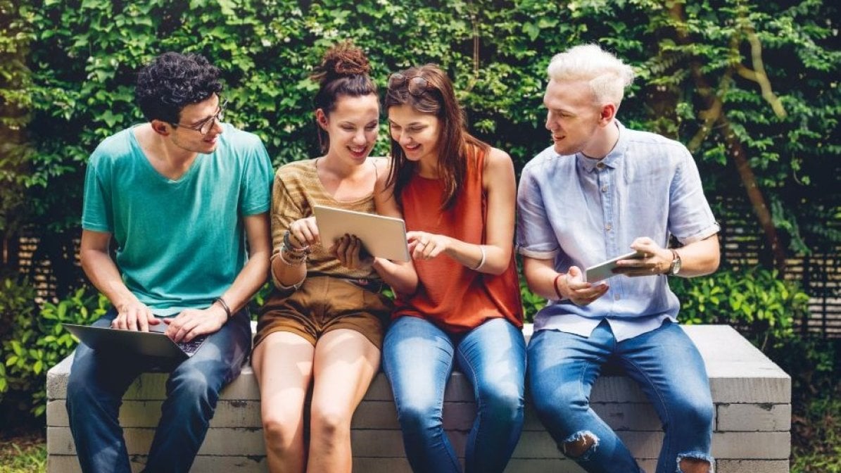 Students sitting on bench checking tablet
