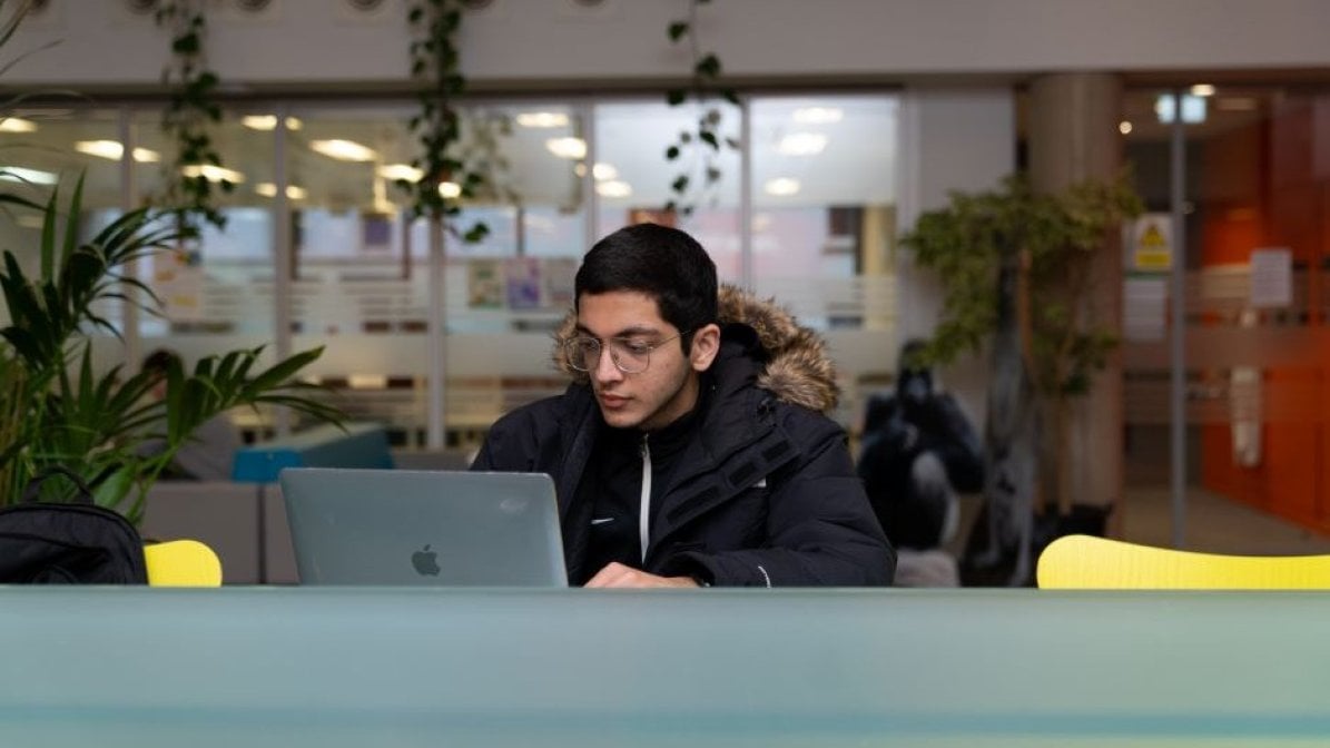 Student using laptop in communal college area