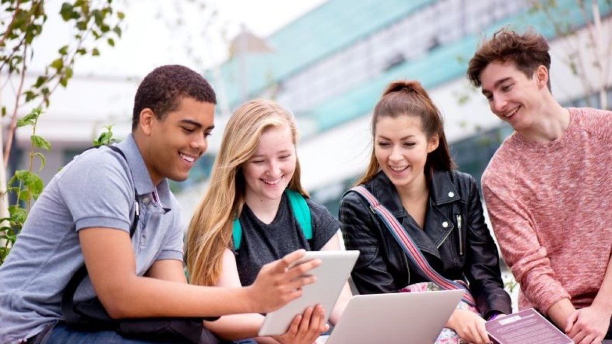 Students sitting outside using laptops 