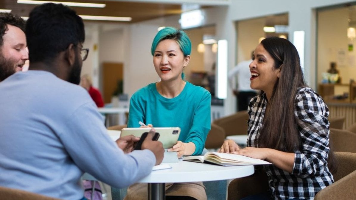 Students chatting around a table in university communal area