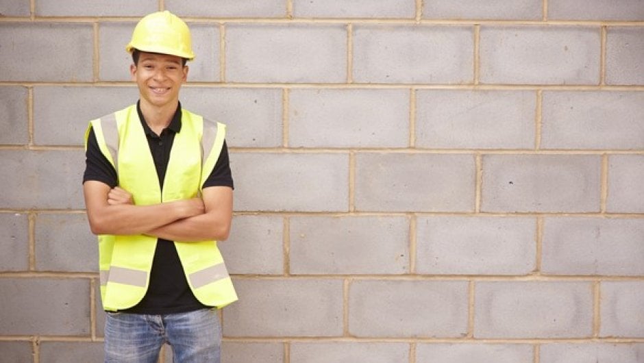 Building and construction apprentice standing against wall