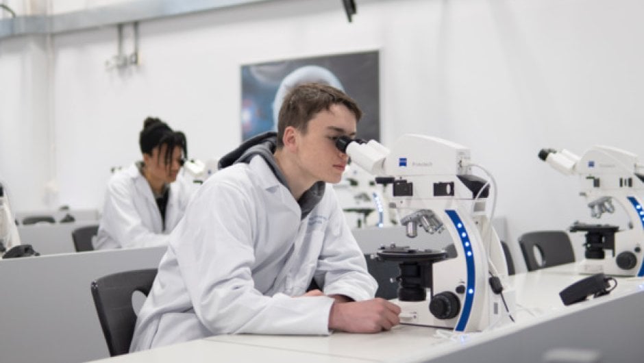 Chemistry apprentice using microscope in lab