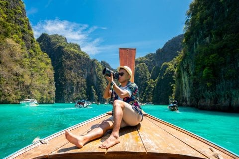 Main taking photographs on boat in Southeast Asia