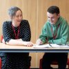 Adviser chatting to student at desk